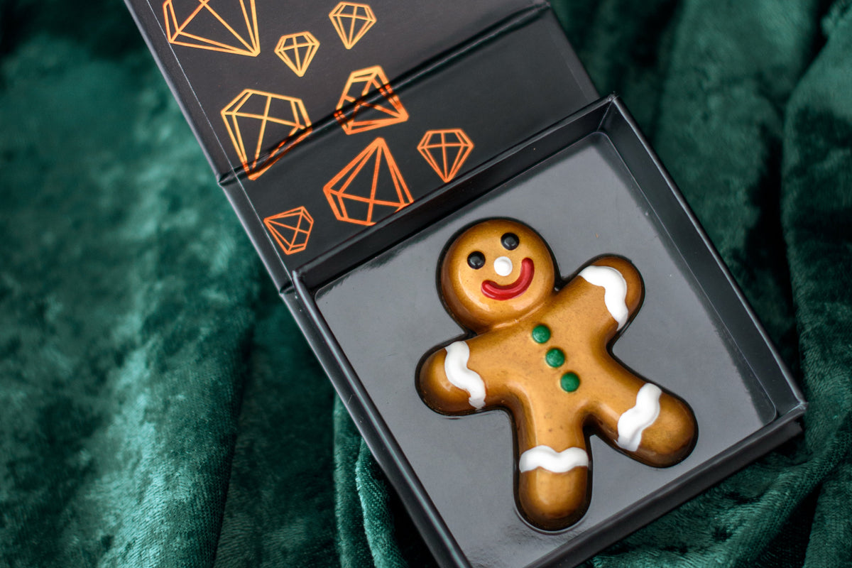 Gingerbread cookie-shaped chocolate bar in a decorative box on a green fabric background