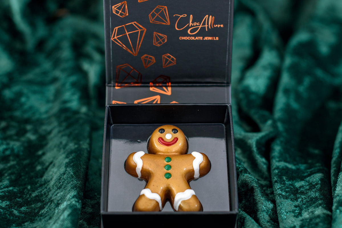 Gingerbread man chocolate figurine in a branded box on a green textured background
